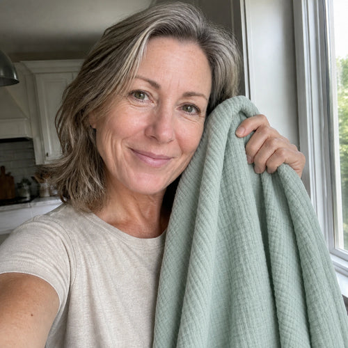 Customer photo: woman holding the Muslin Blanket in Green up beside her face