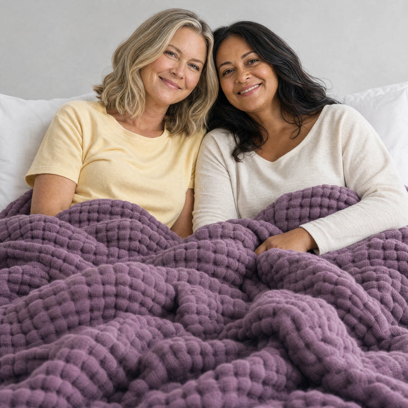 Two women in bed under the Muslin Blanket in Purple