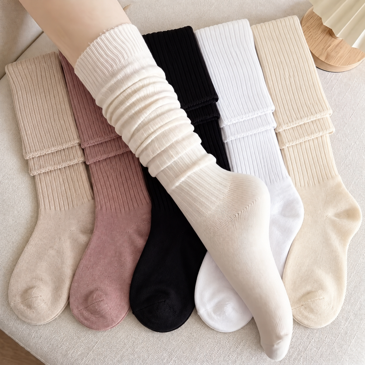 White ribbed lounge sock worn softly scrunched, with Beige, Dusty Rose, Black, White and Cream socks on ivory linen.