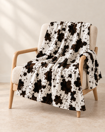 Cow Print patterned throw draped over an oatmeal linen and pale oak chair