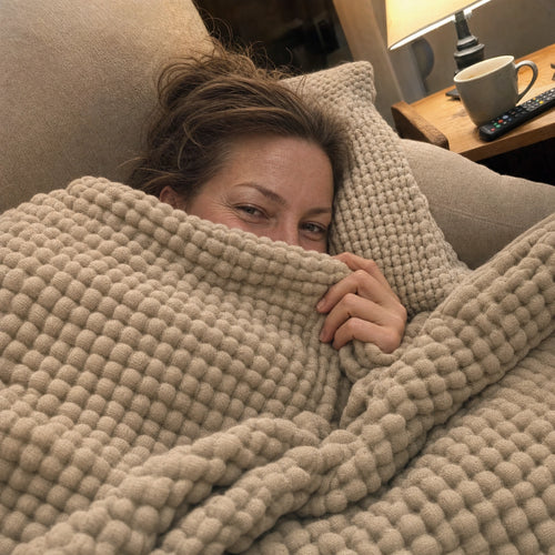 Customer photo: woman resting on a couch under the Muslin Blanket in Dune