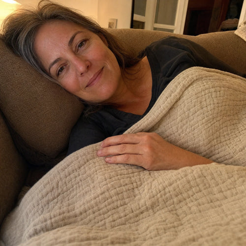 Customer photo: woman resting on a couch under the Muslin Blanket in Dune