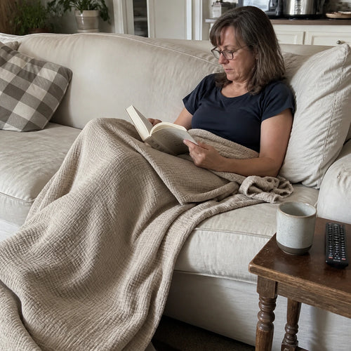 Customer photo: woman resting on a couch under the Muslin Blanket in Dune