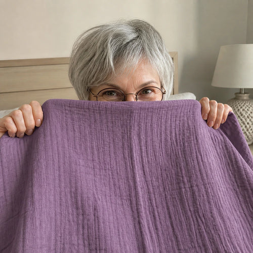Customer photo: woman in glasses peeking over the Muslin Blanket in Purple