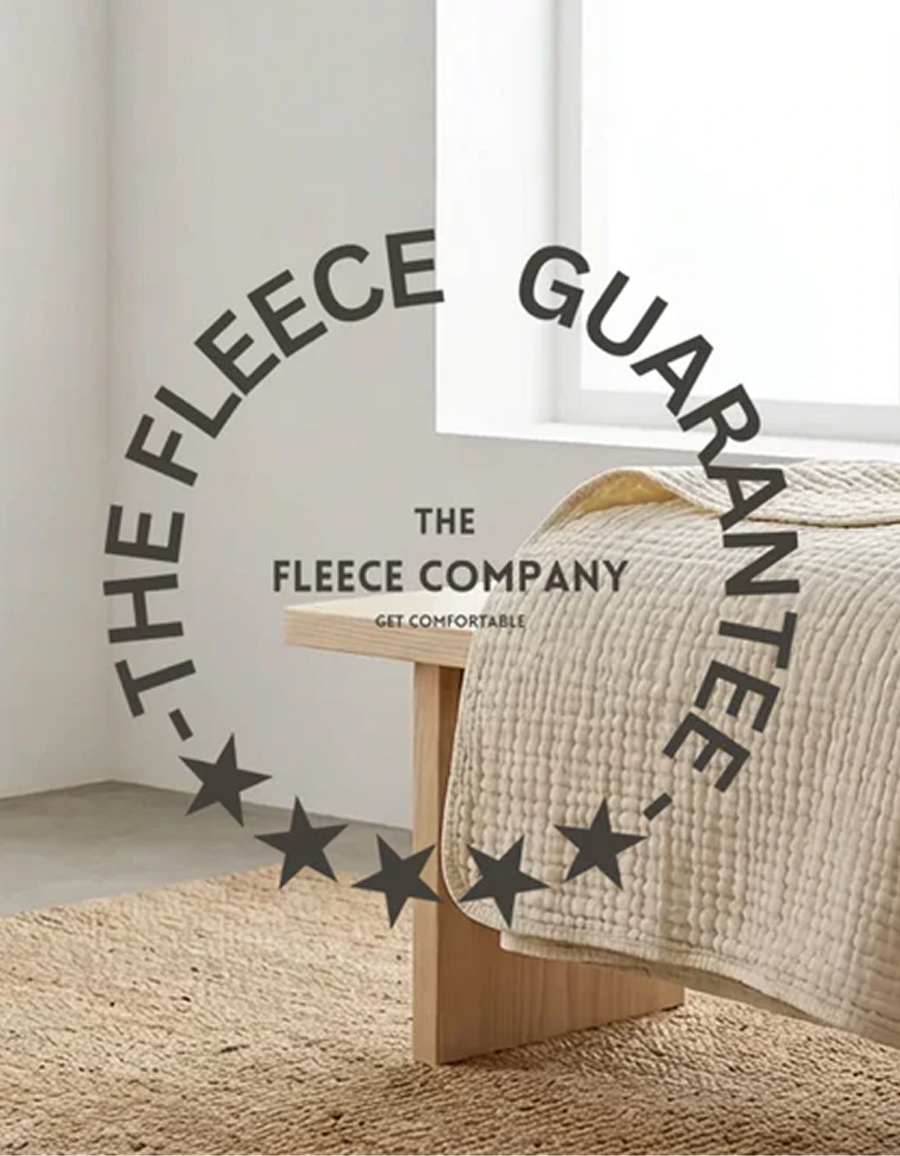 The Fleece Company guarantee seal over a muslin cotton blanket on a bed