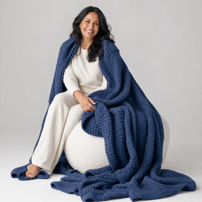 Woman on a pouf with the Muslin Blanket in Navy draped to the floor