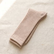 Beige ribbed lounge socks folded on ivory linen; colour reference for a pack of five matching pairs.