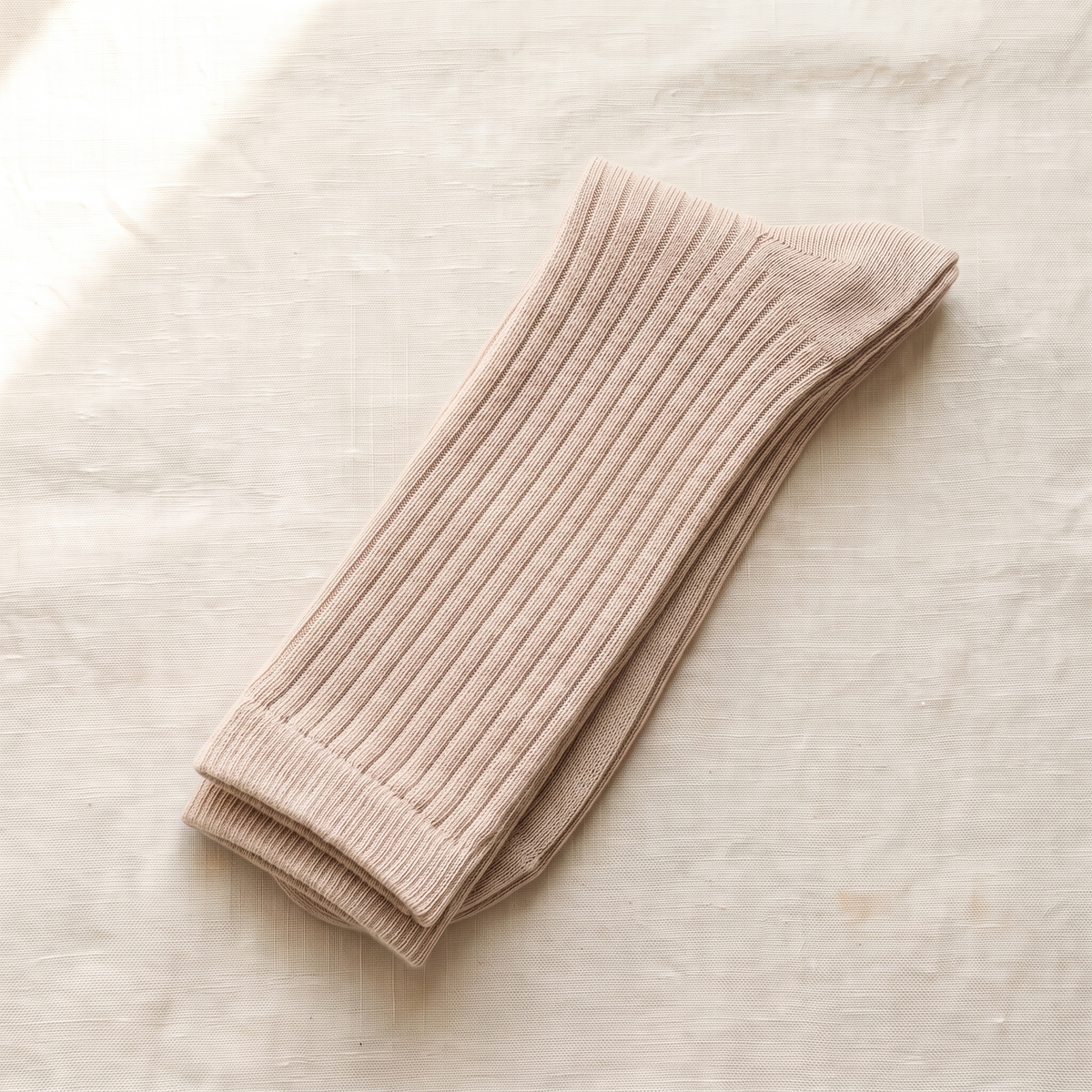 Beige ribbed lounge socks folded on ivory linen; colour reference for a pack of five matching pairs.