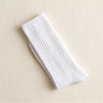 White ribbed lounge socks folded on ivory linen; colour reference for a pack of five matching pairs.