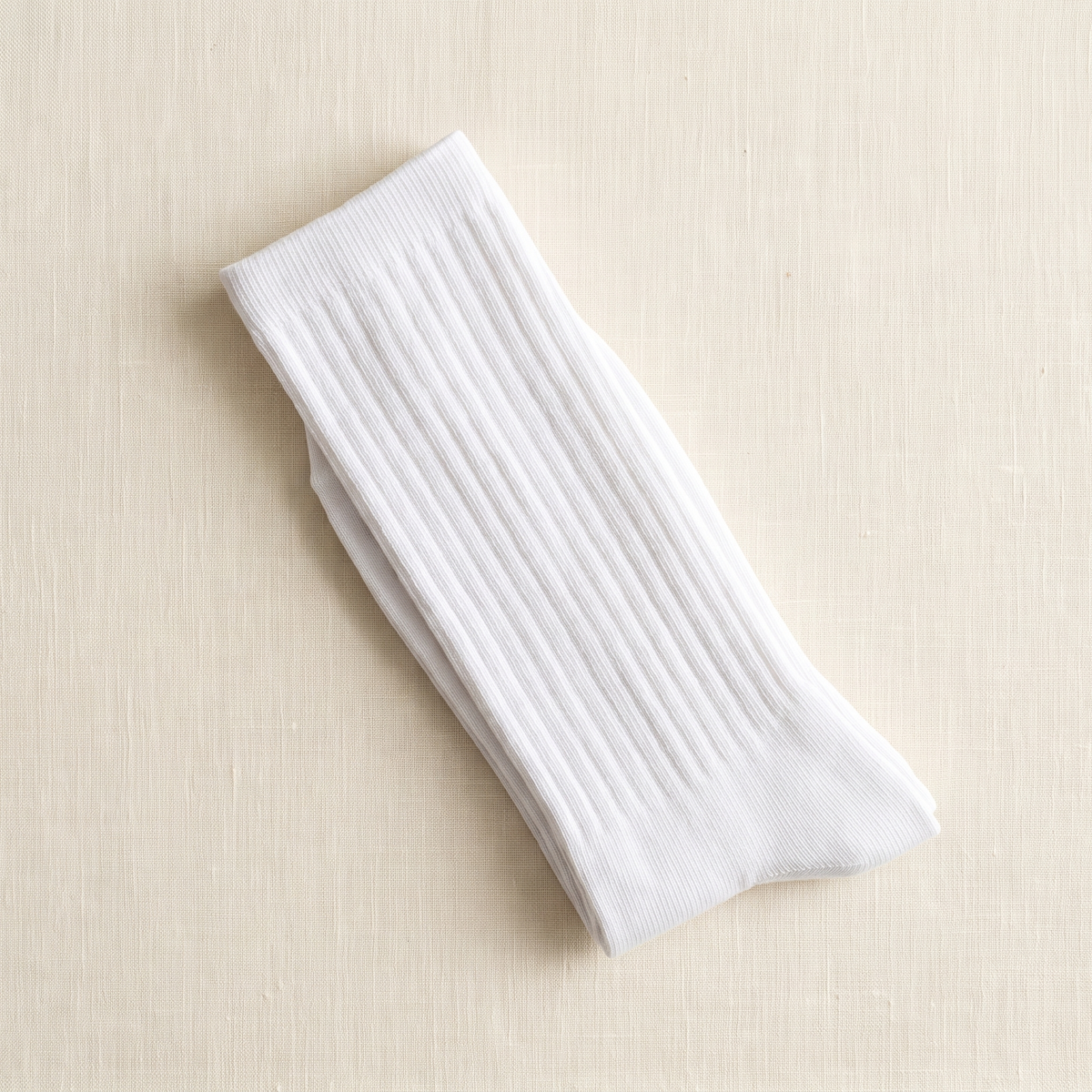 White ribbed lounge socks folded on ivory linen; colour reference for a pack of five matching pairs.